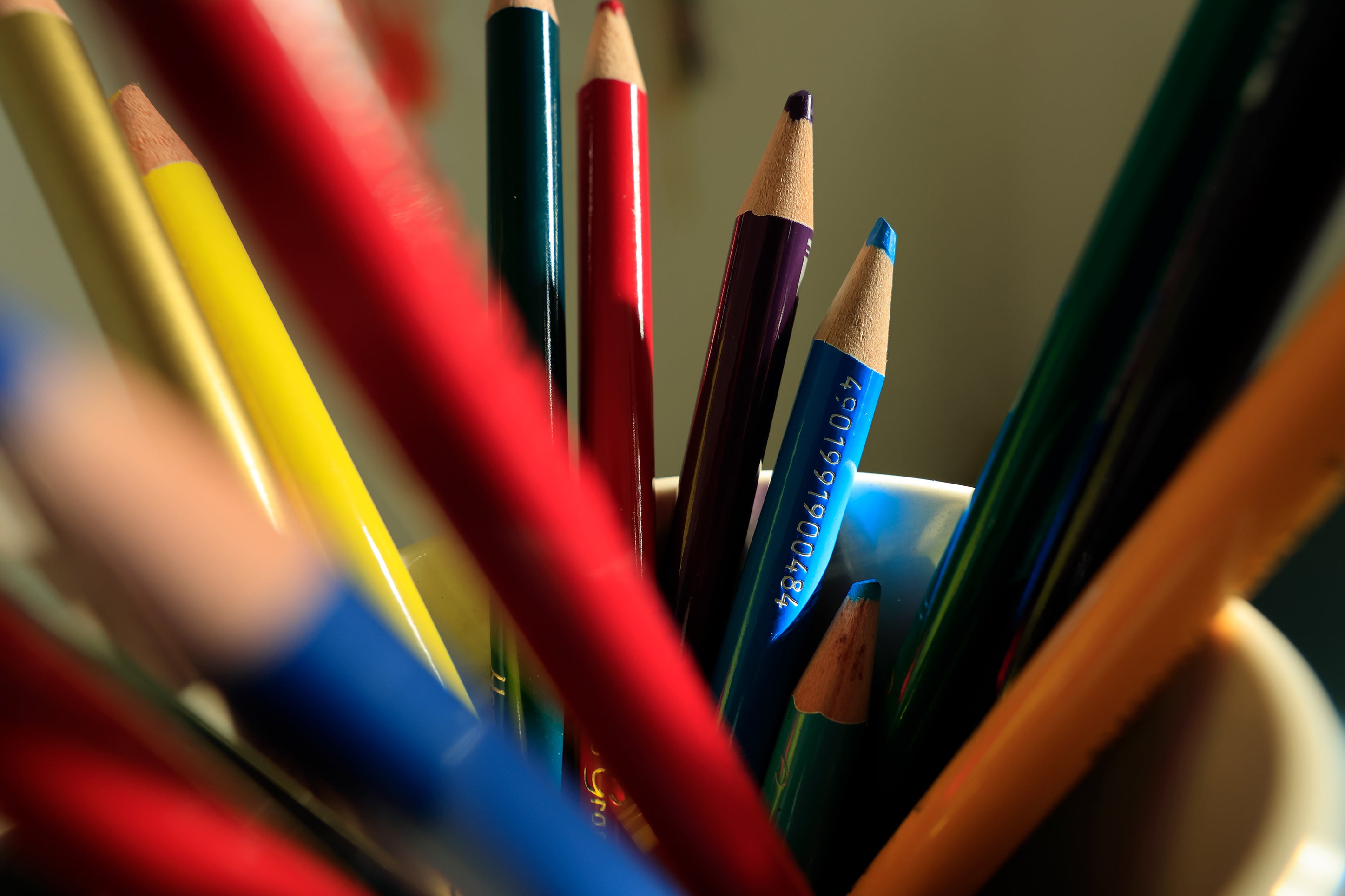 Assorted colored pencils in a cup with a blurred background